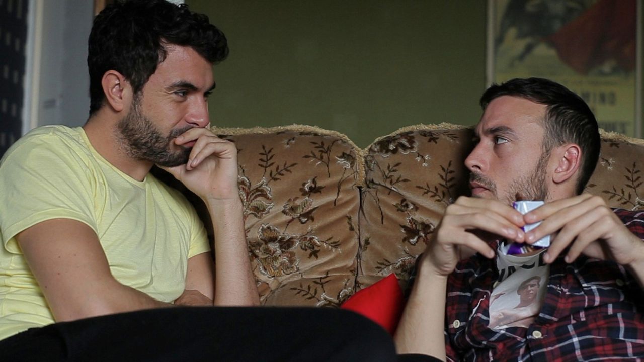 Russell e Glen conversando no sofá no filme Weekend de 2011.