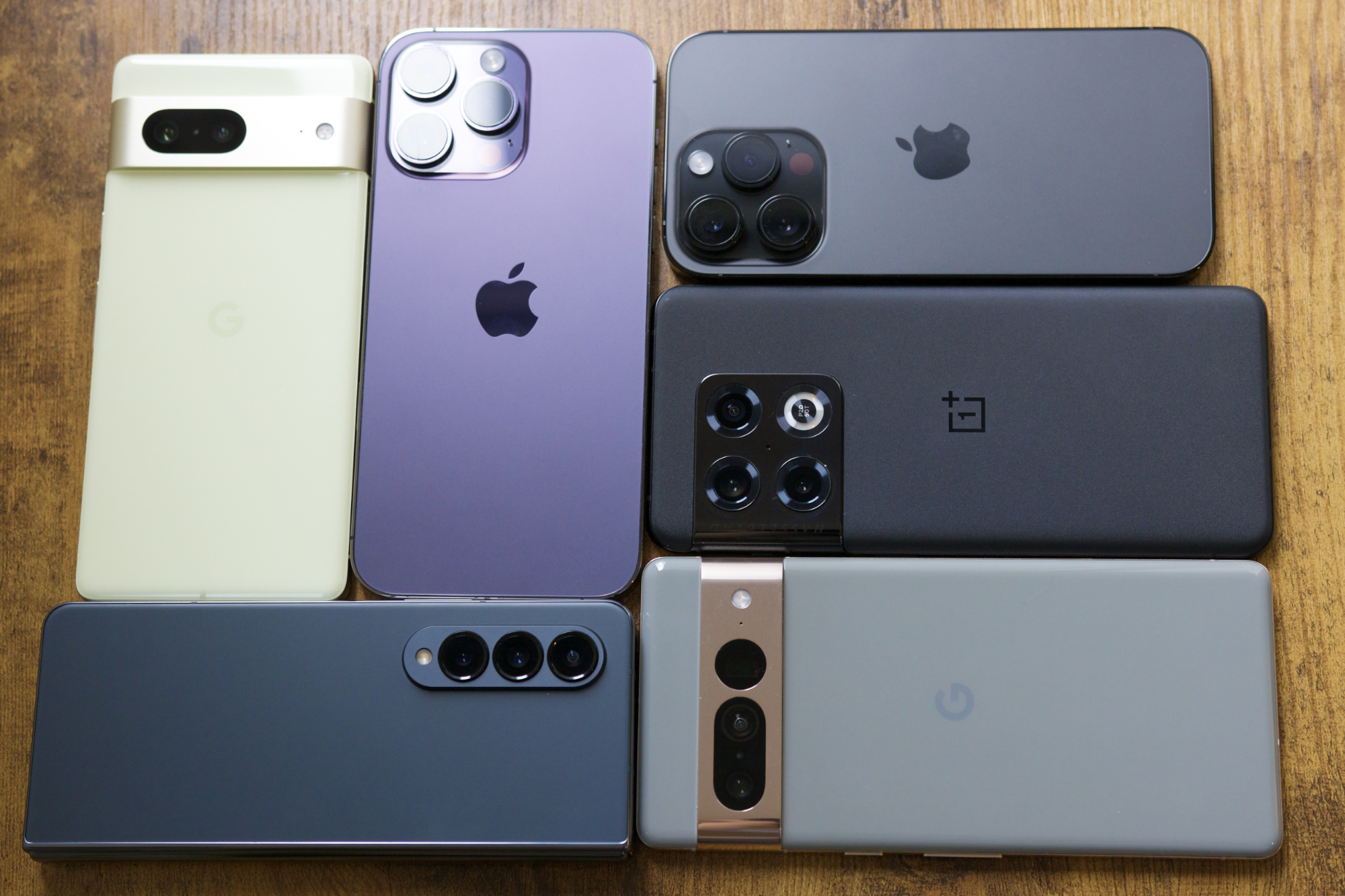 Google Pixel 7, iPhone 14 Pro Max, iPhone 14 Pro, Pixel 7 Pro, OnePlus 10 Pro e Galaxy Z Fold 4, todos sobre uma mesa.