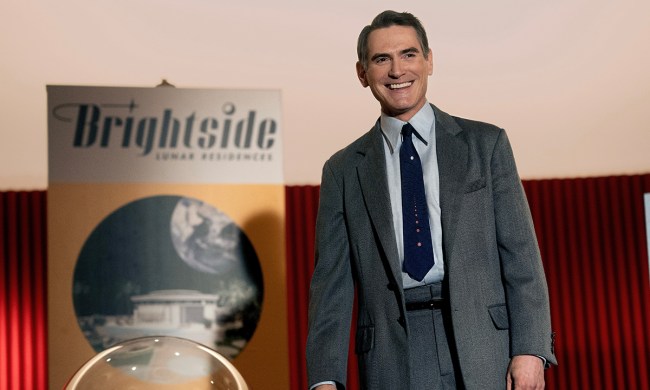 Billy Crudup standing in a suit beside a sign that says Brightside in a scene from Apple TV+ series Hello Tomorrow.