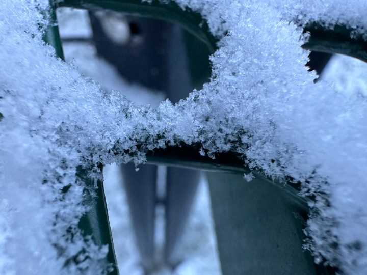 Macro photo of snow on a green picnic table.