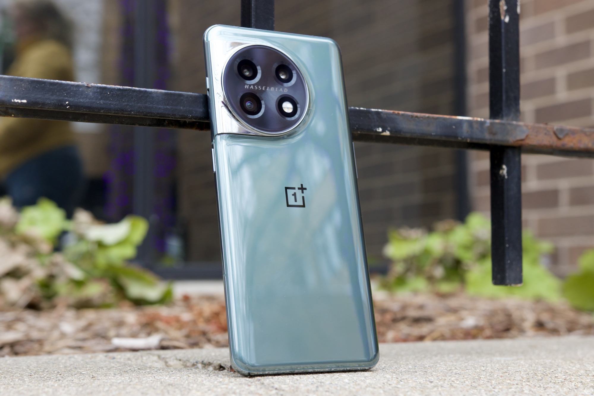 Le OnePlus 11, reposant debout contre un rail métallique.