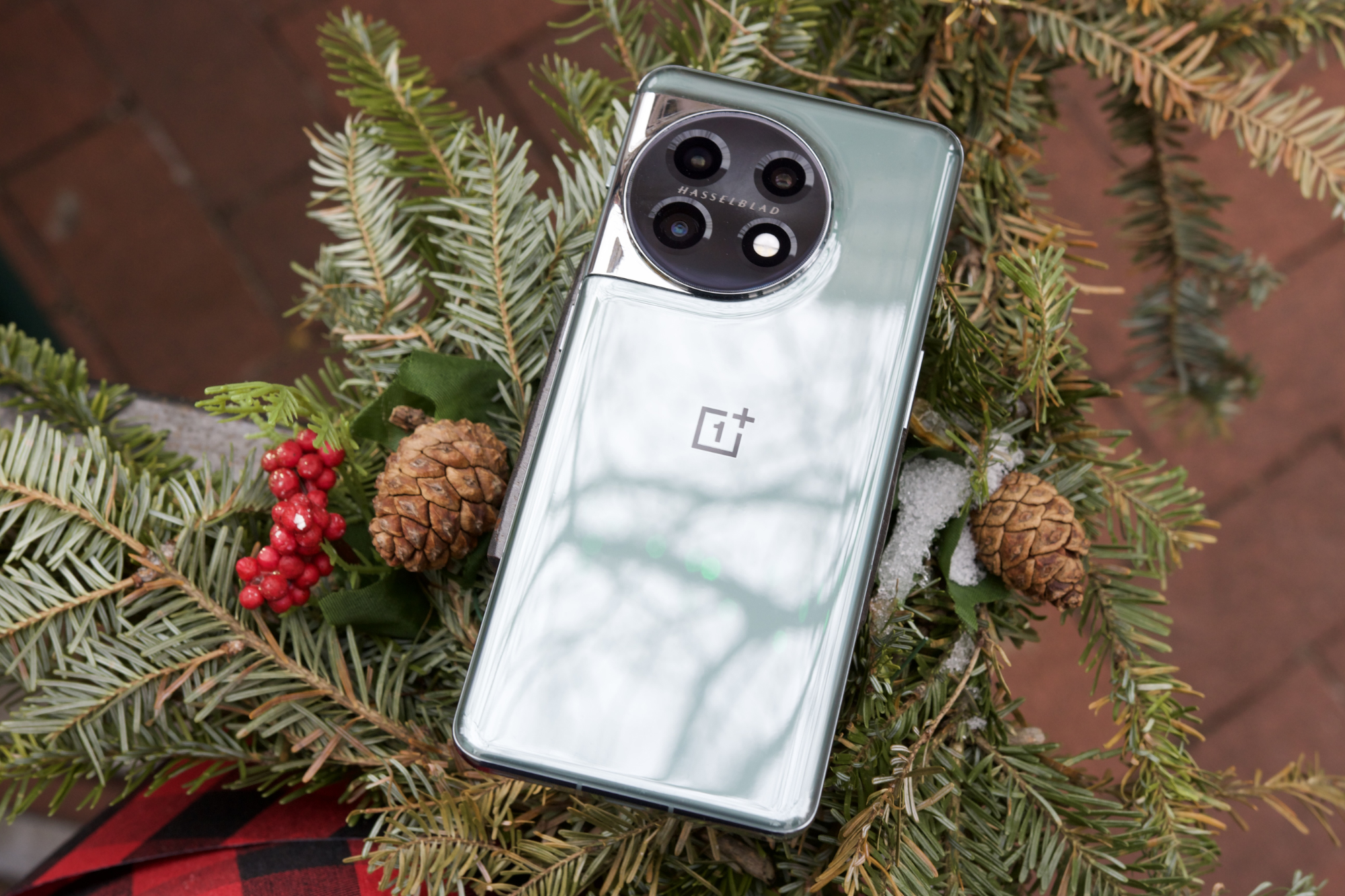 O OnePlus 11 virado para baixo em uma grade com decorações de Natal.