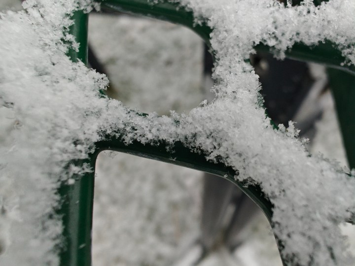 Macro photo of snow on a green picnic table.