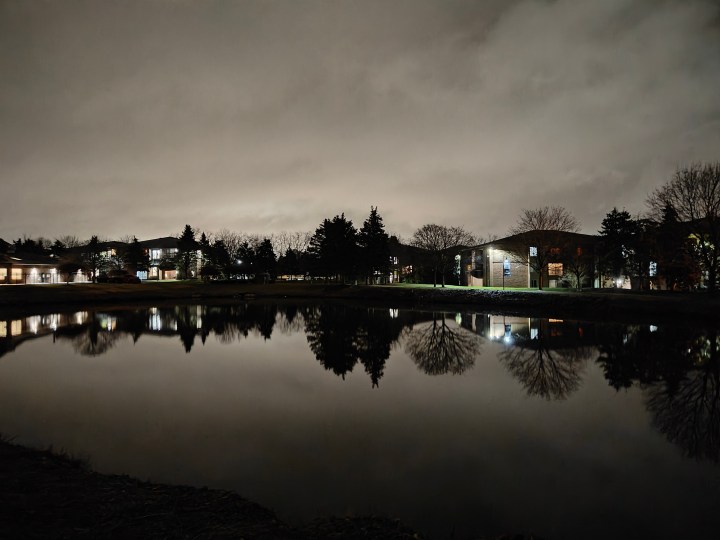 Night mode photo of a pond and overcast skies.