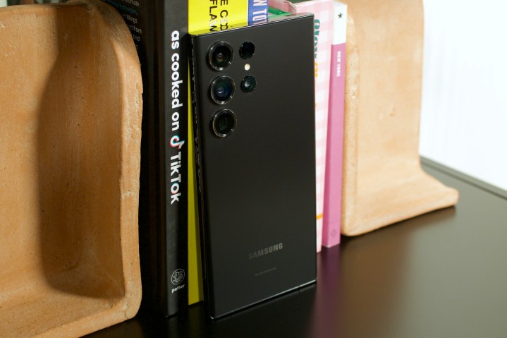 Samsung Galaxy S23 Ultra مشکی که در مقابل ردیفی از کتاب ها ایستاده است.