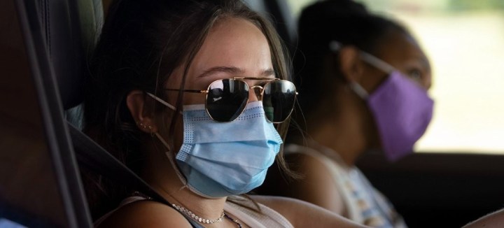 Two girls wear masks while in a car in Sick.