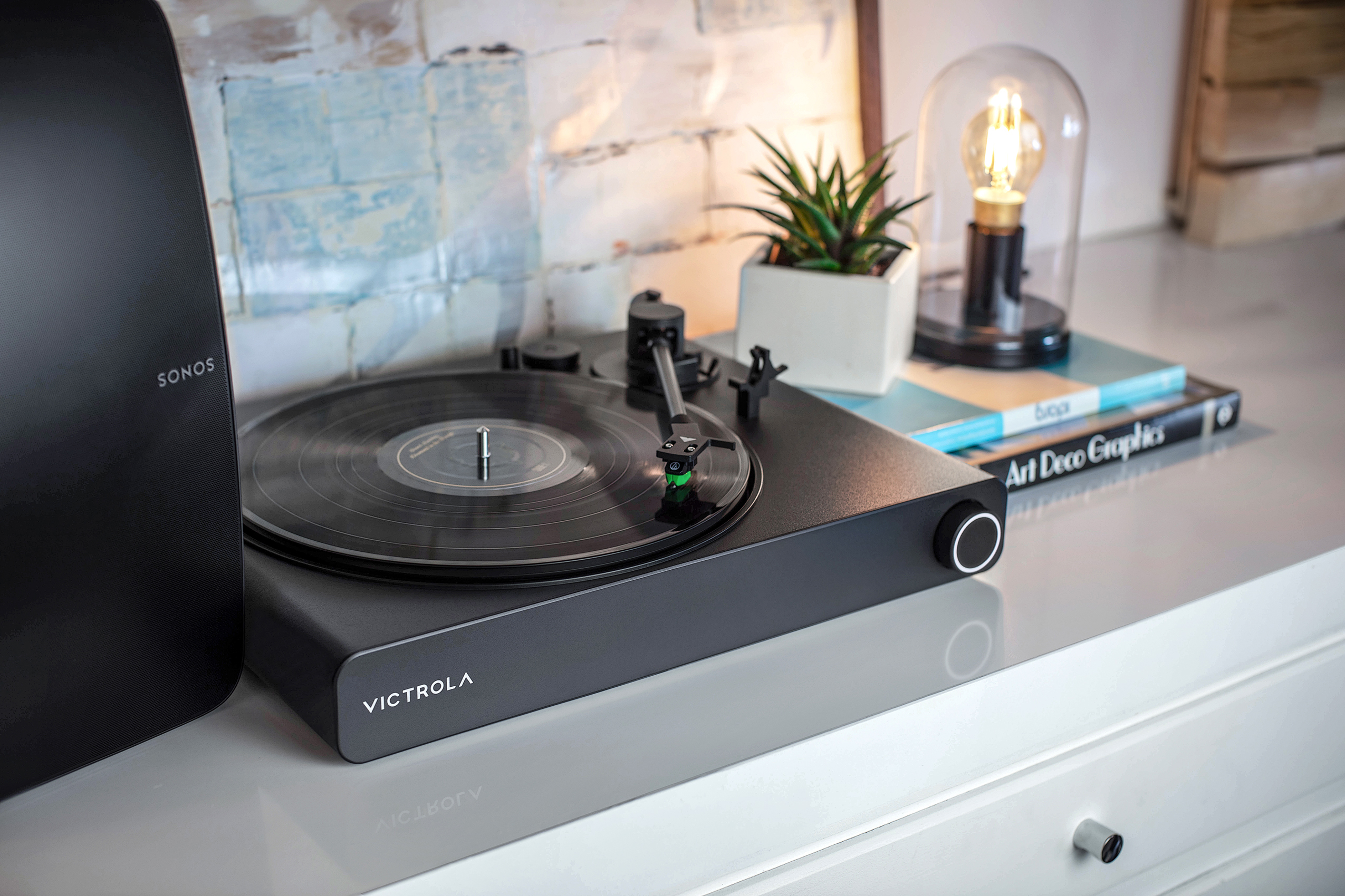 The Victrola Stream Onyx Sonos-ready turntable on a white cabinet.