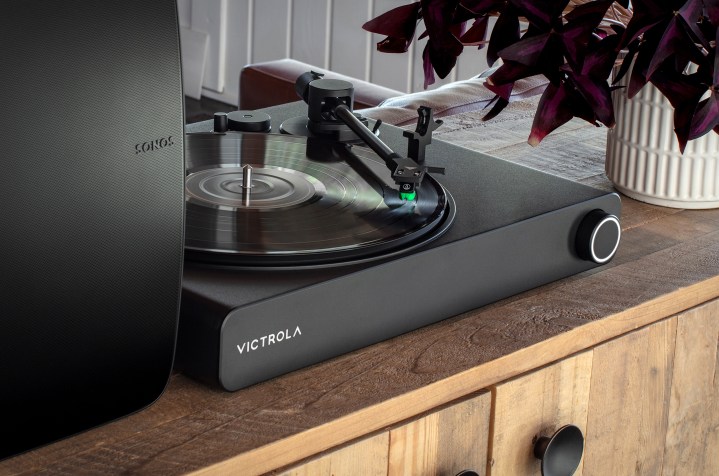The Victrola Stream Onyx Sonos-ready turntable on a wood cabinet with a Sonos Five.