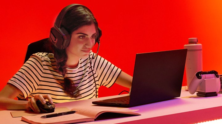Una mujer se sienta junto a un escritorio y juega un juego en una computadora portátil equipada con un procesador AMD.