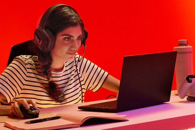 تجلس امرأة بجوار مكتب وتلعب لعبة على جهاز كمبيوتر محمول مجهز بمعالج AMD