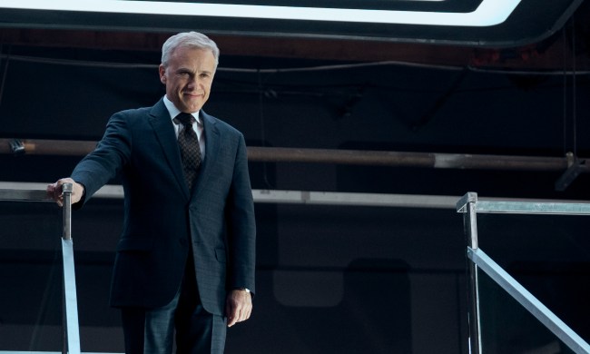 Christoph Waltz stands at the top of a staircase in The Consultant.