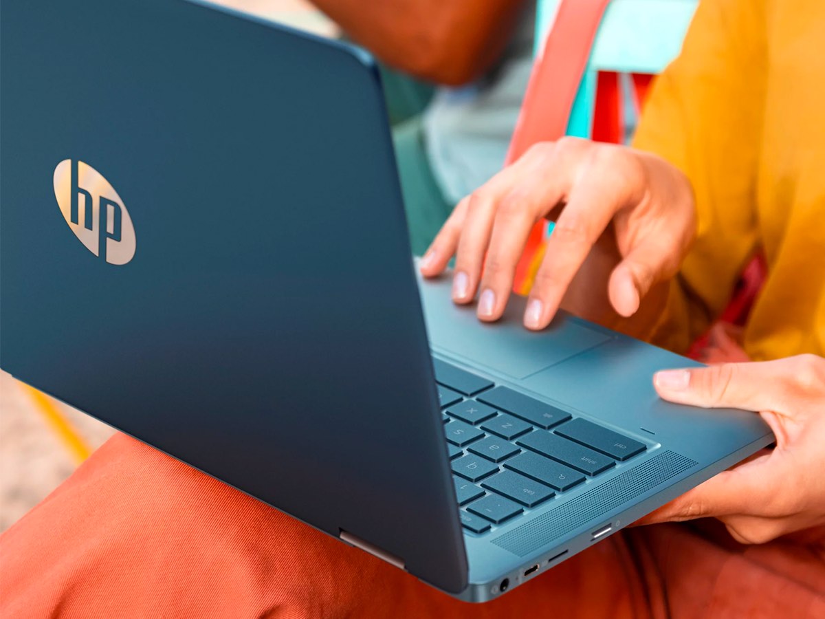 A woman uses the trackpad of the HP 14-inch 2-in-1 touch laptop.