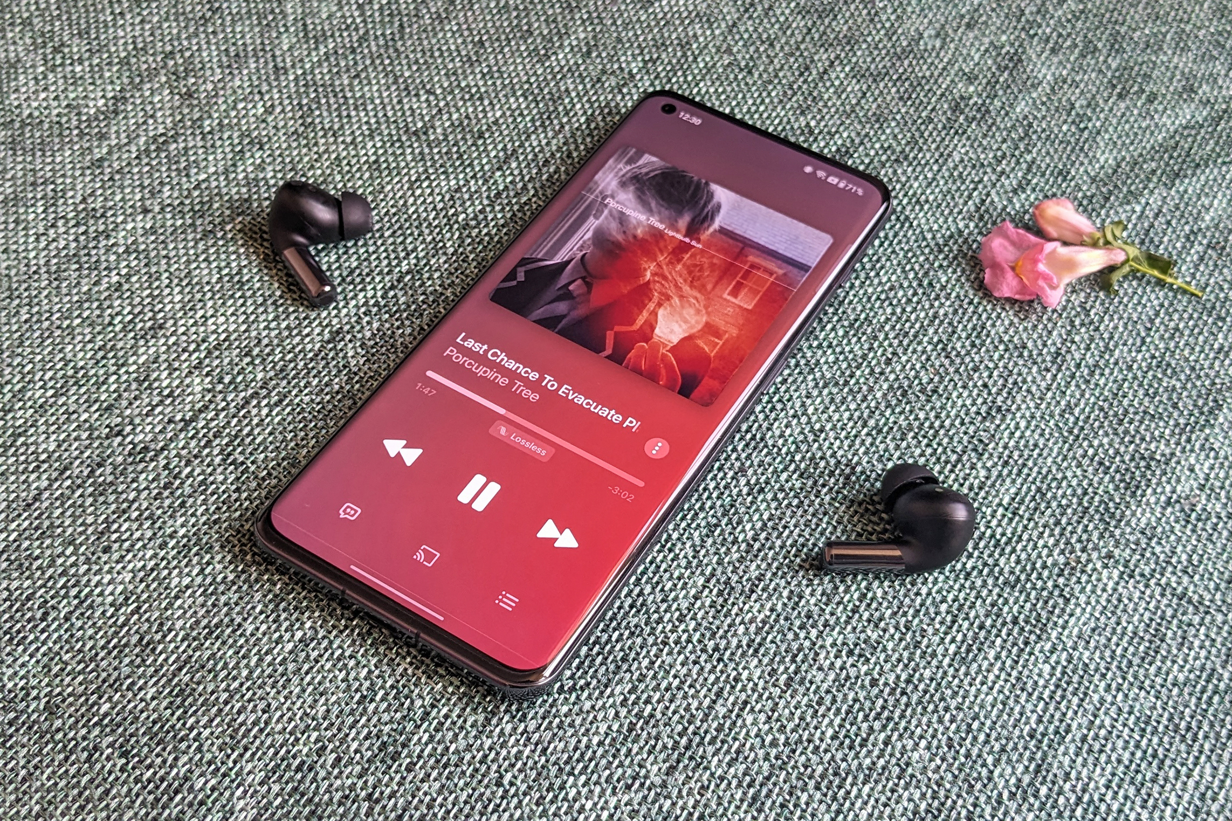 Apple Music com faixa de música de áudio sem perdas tocando no OnePlus 11 junto com o OnePlus Buds Pro 2 na cor preta sobre uma superfície de tecido verde.
