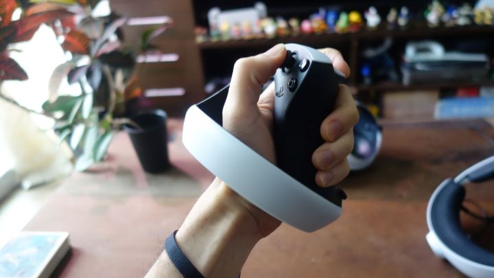 A hand holds a PlayStation VR2 Sense controller.