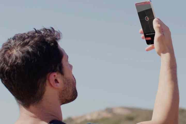 Hombre sosteniendo el teléfono inteligente hacia el cielo para obtener una solución satelital.
