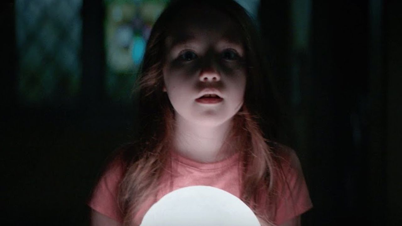 Uma jovem segurando uma lâmpada e parecendo assustada no filme The Boogeyman.