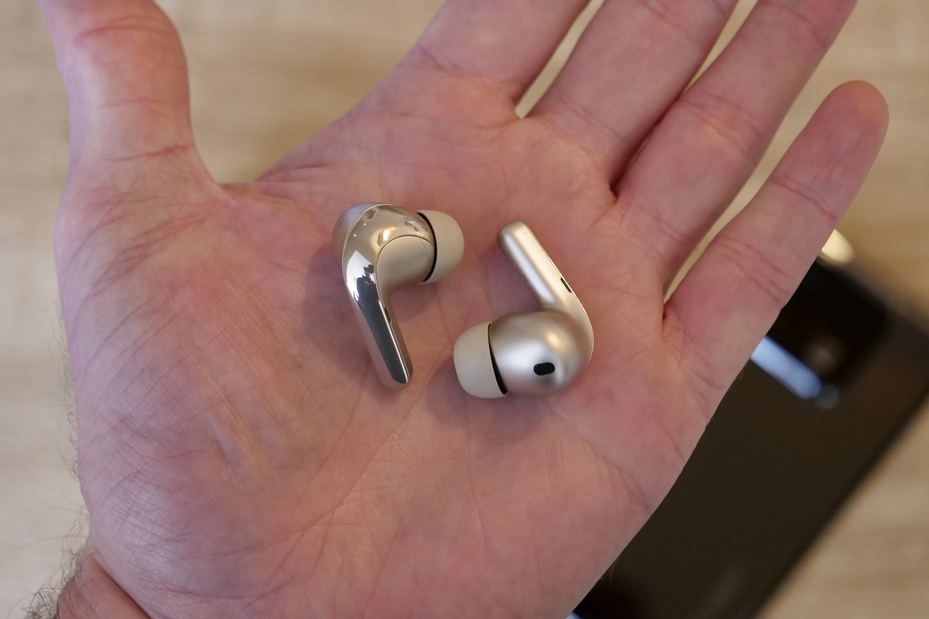 The Xiaomi Buds 4 Pro earbuds in the palm of a person's hand.