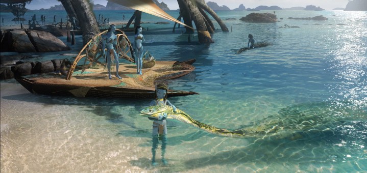 A child Na'vi cradles a sea creature on the beach in a scene from Avatar: The Way of Water.