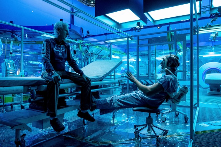 James Cameron se sienta en un escritorio discutiendo una toma con un actor durante el rodaje de Avatar: The Way of Water.