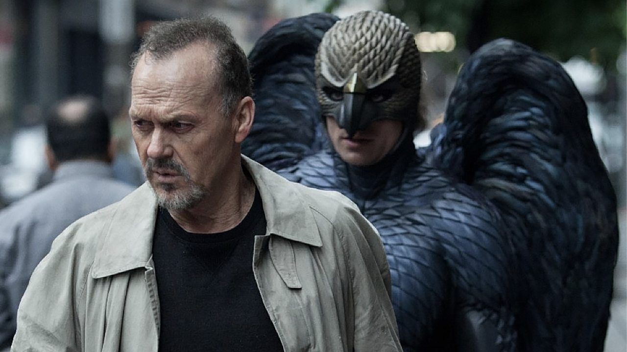 Michael Keaton sendo seguido por um homem fantasiado de pássaro em uma cena de Birdman.