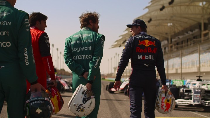 Several drivers, including Max Verstappen of team Red Bull, walk along the track, holding their helmets, in a scene from season 5 of Formula 1: Drive to Survive.