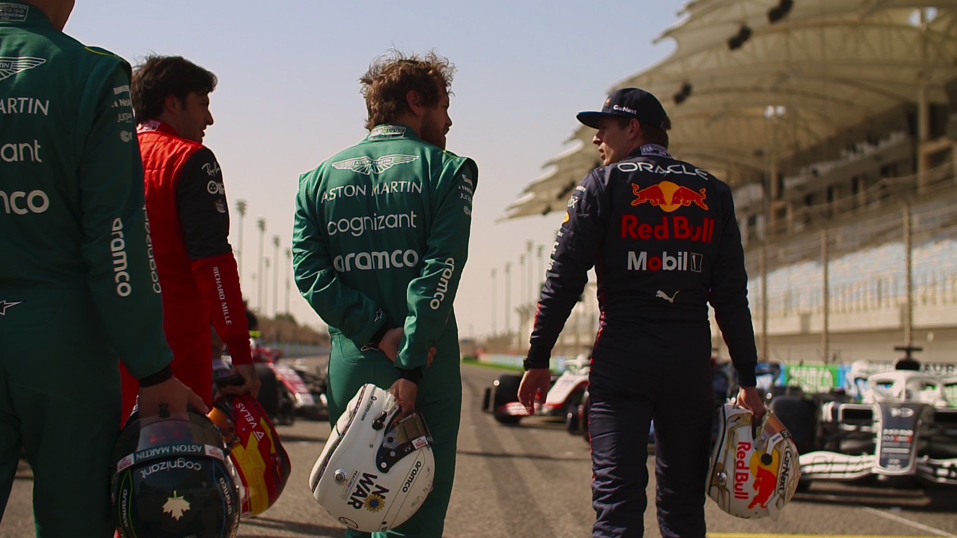 Vários pilotos, incluindo Max Verstappen, da equipe Red Bull, caminham pela pista, segurando seus capacetes, em uma cena da 5ª temporada da Fórmula 1: Drive to Survive.