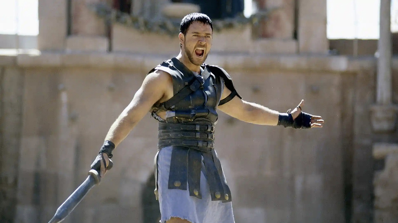 Russell Crowe em pé e gritando em uma cena de Gladiador.