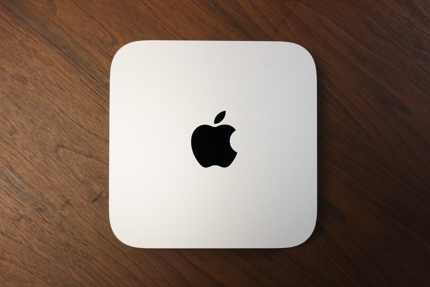 Uma visão de cima para baixo do Mac mini em uma superfície de madeira.