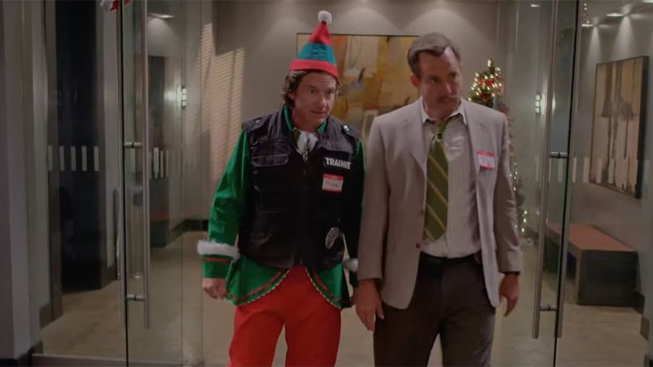 Jason Bateman dressed like an elf standing with Will Arnott in a blazer and tie in a scene from Murderville on Netflix.