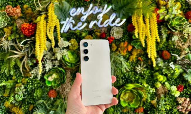 Samsung Galaxy S23 held in hand against green floral backdrop
