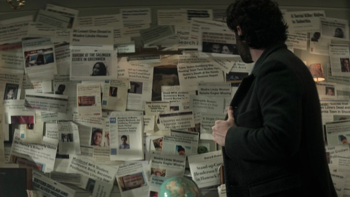 Joe von You looks at a collage of old newspaper articles on his wall in season 4.