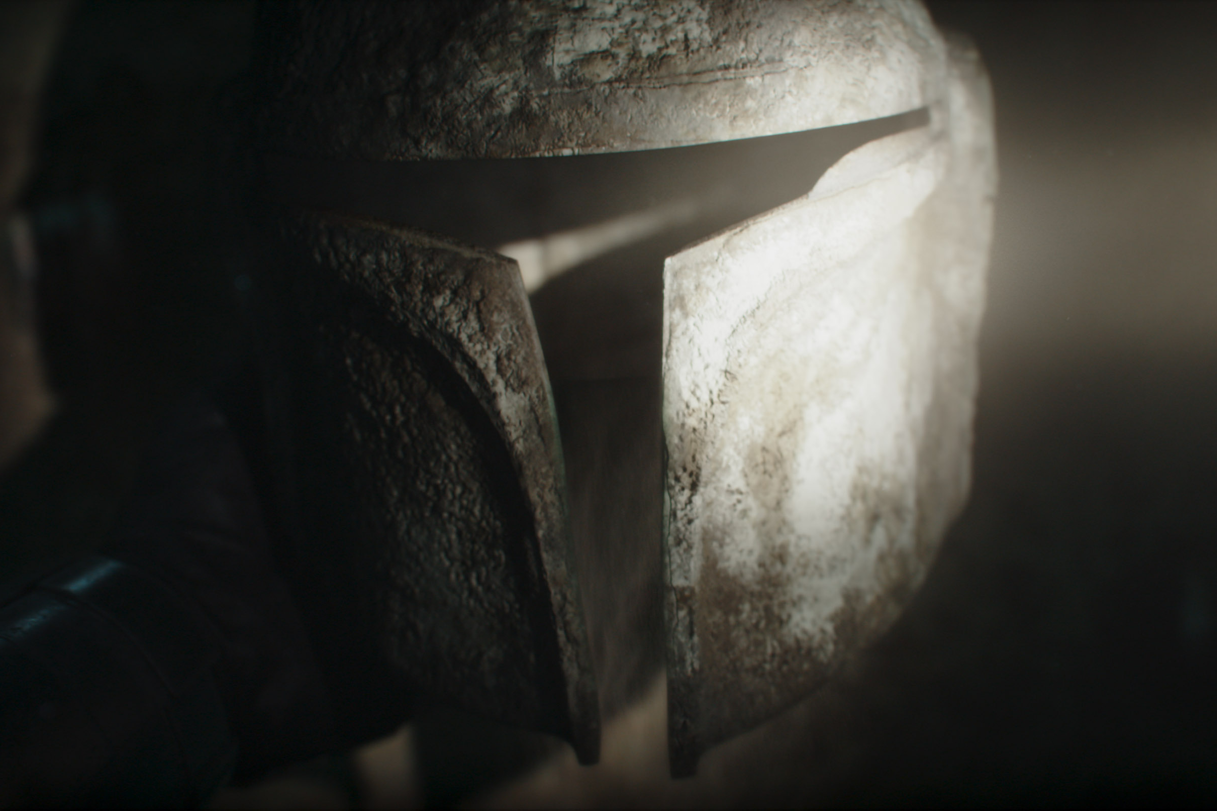 A ray of light shines on an old Mandalorian helmet in The Mandalorian Season 3 Episode 2