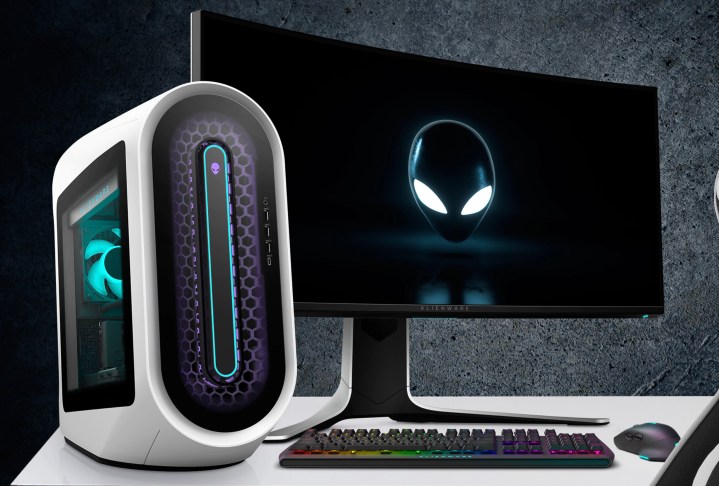 The Alienware Aurora R13 gaming desktop on a desk next to a monitor.