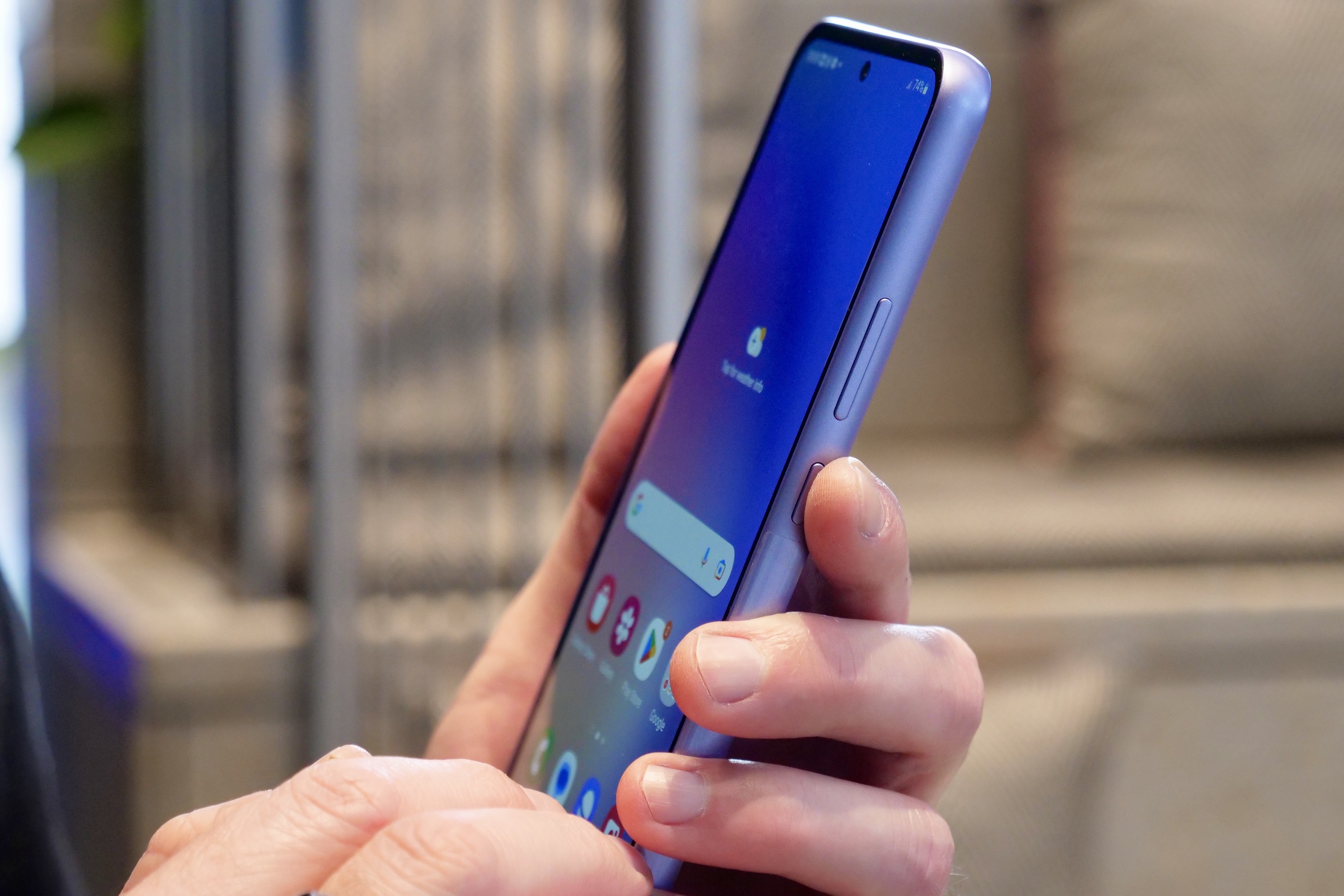 A person holding the Galaxy A54, showing the button position.