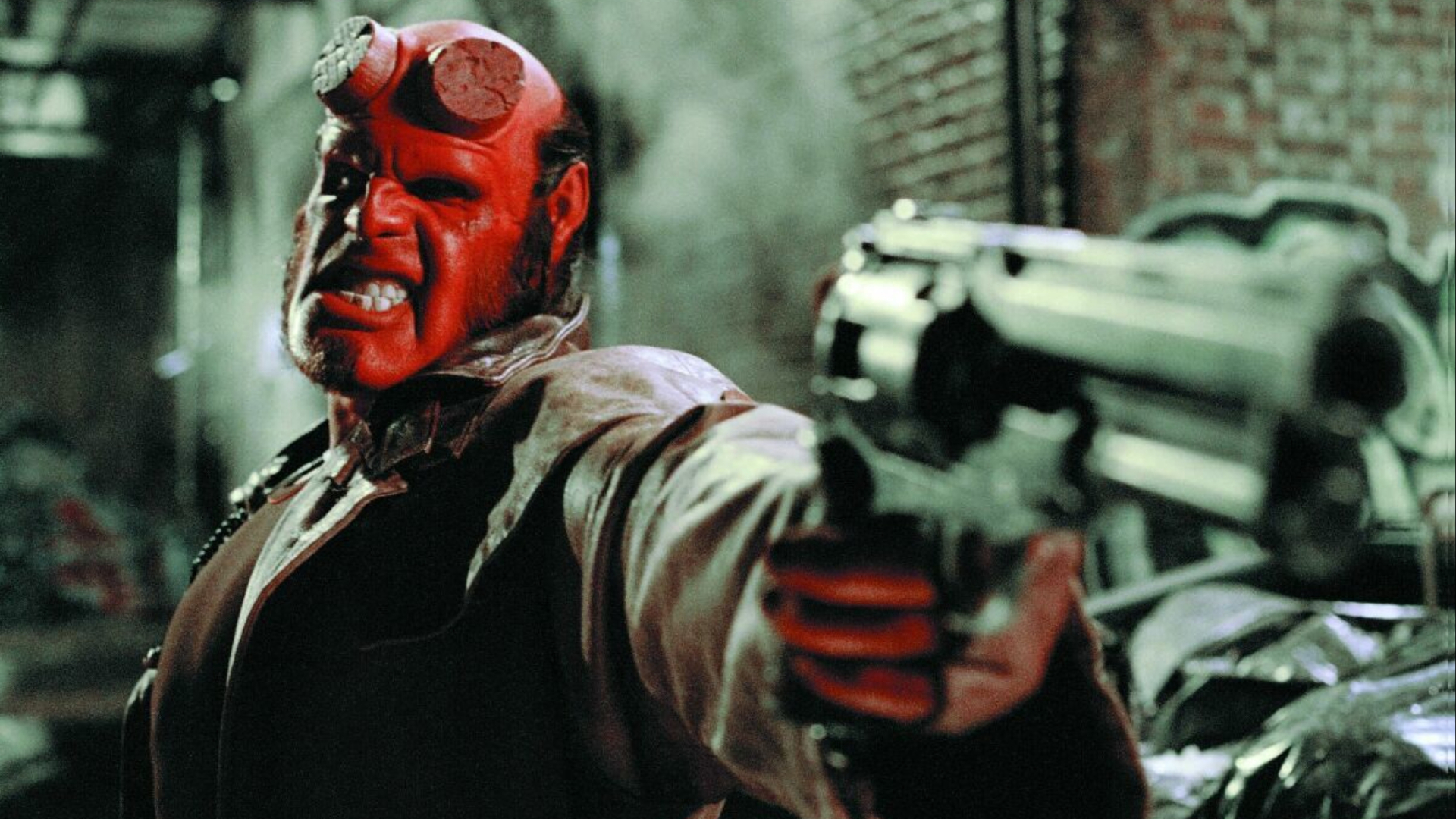Hellboy rangendo os dentes e apontando sua arma.
