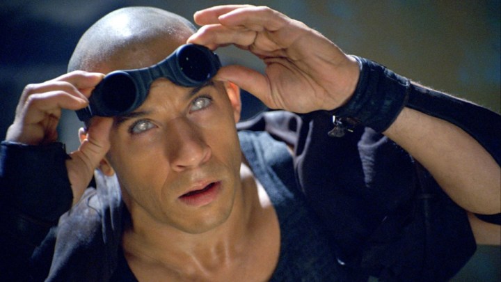 Vin Diesel's Riddick holds up his glasses in The Chronicles of Riddick.