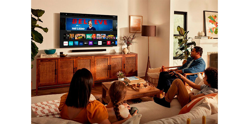 लिविंग रूम में विज़िओ 75-इंच वी-सीरीज़ टीवी को पूरा परिवार देख सकता है।