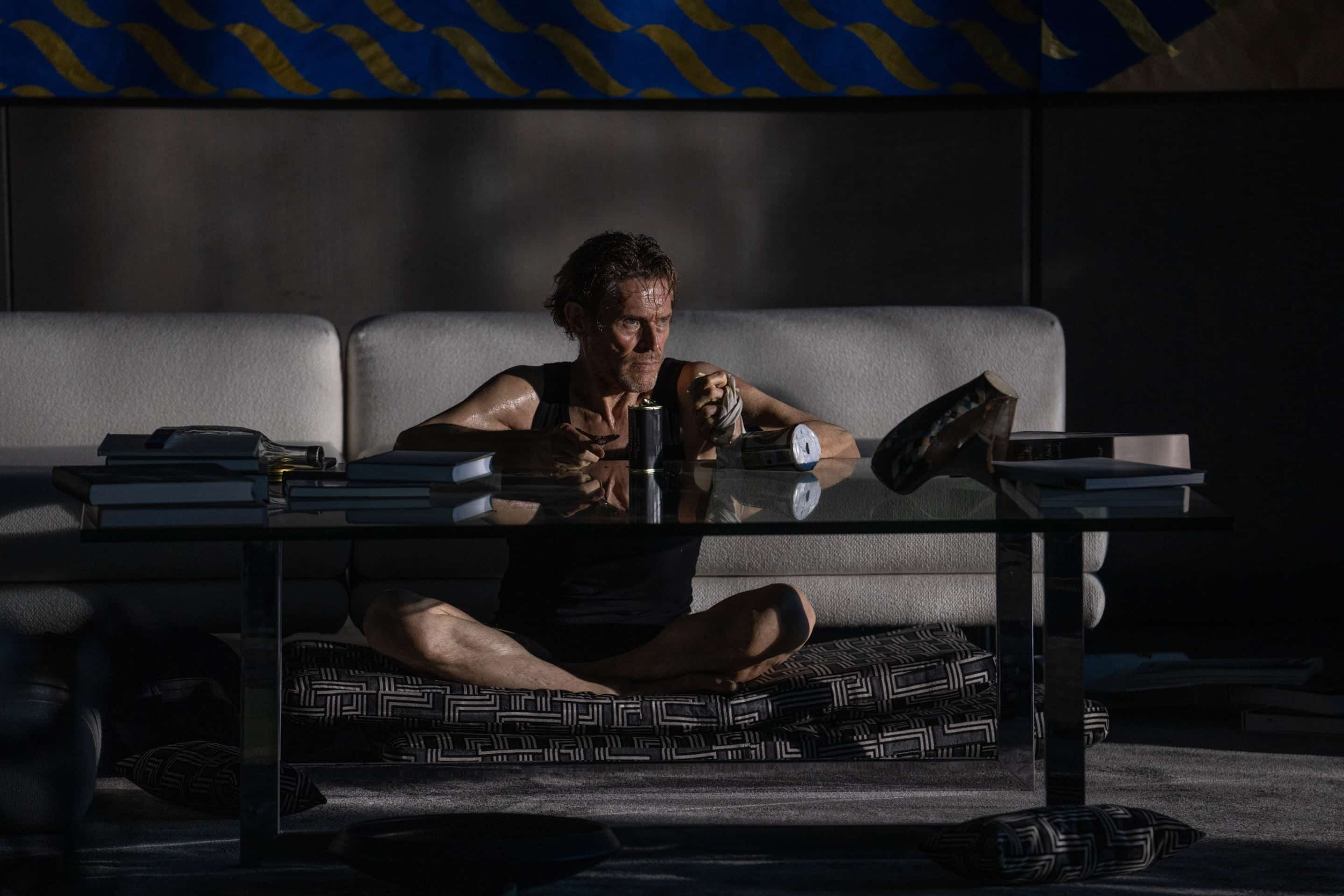 Willem Dafoe sits in front of a table in Inside.