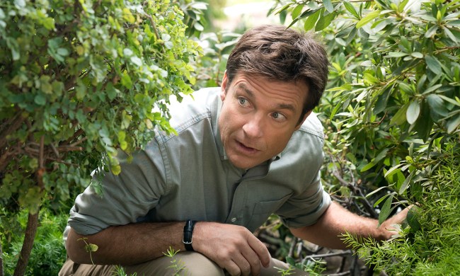 Jason Bateman peaking through some bushes in a scene from Arrested Development.