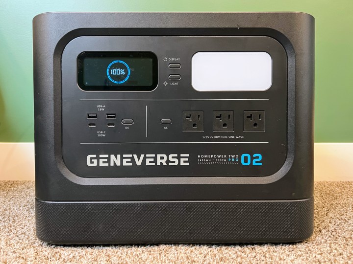 A Geneverse HomePower Two Pro power station is set in front of a green wall.