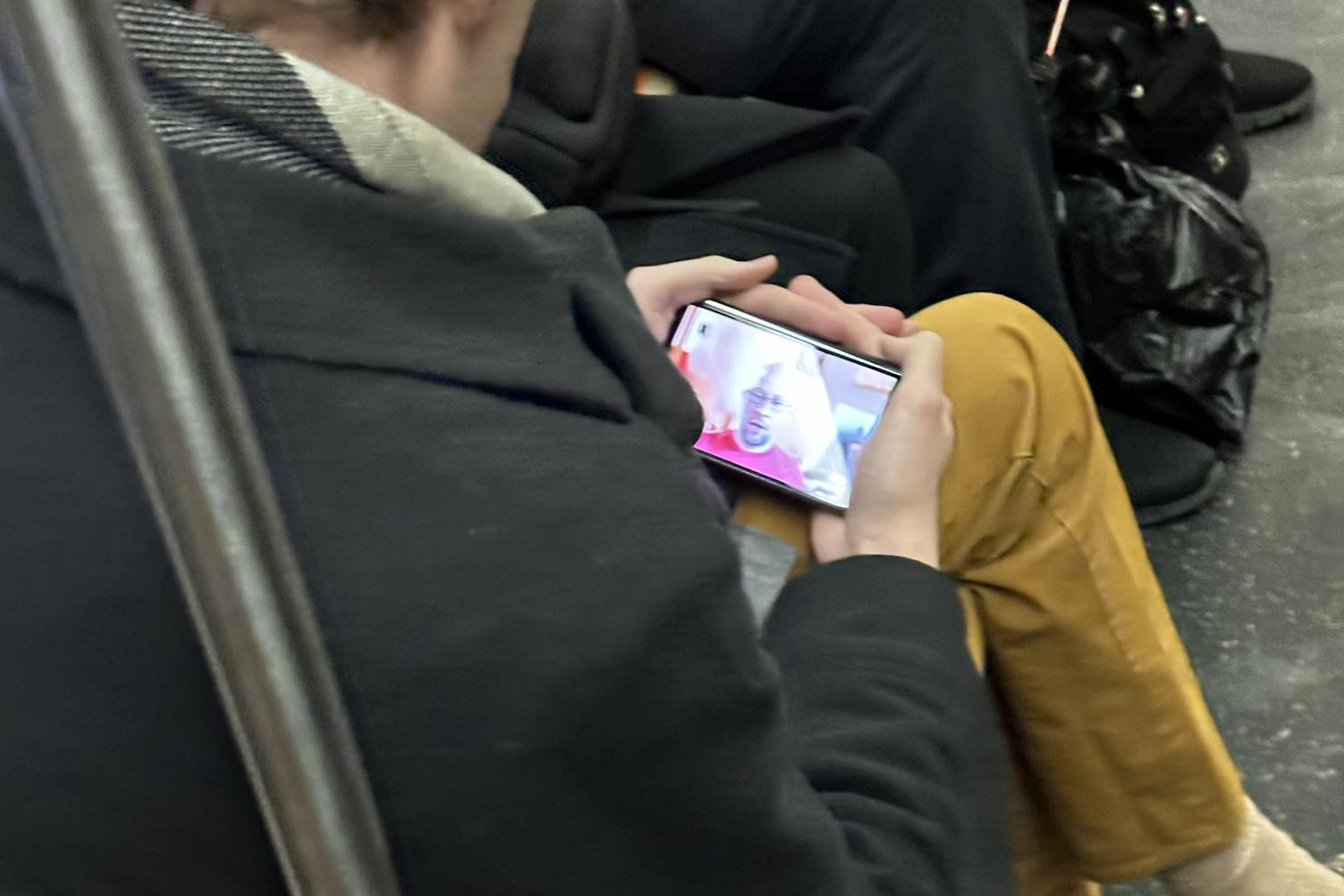 Someone holding a smartphone, allegedly the Google Pixel Fold, on a subway.