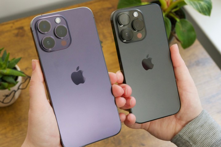 A person holding an iPhone 14 Pro Max and an iPhone 14 Pro next to each other.