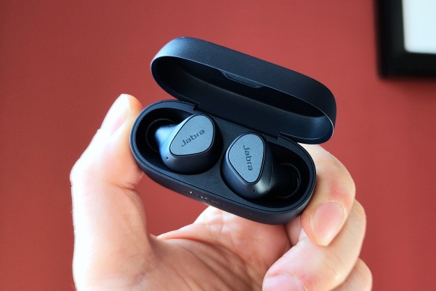Jabra Elite 4 in an open charging case held by a hand.
