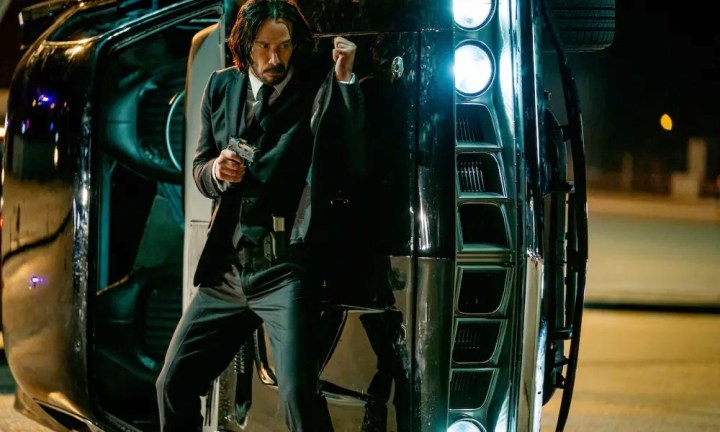 John Wick está atrás de um carro em John Wick: Capítulo 4.