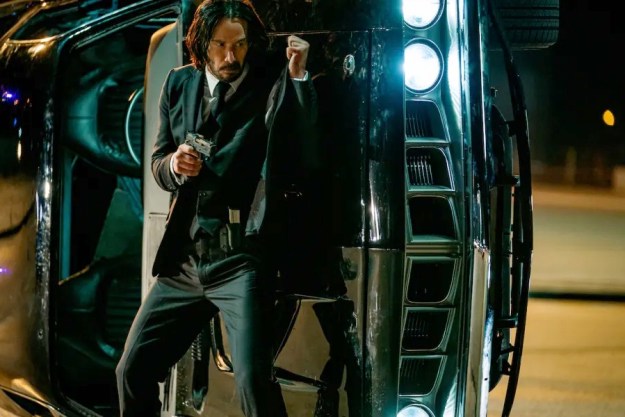 John Wick stands behind a car in John Wick: Chapter 4.