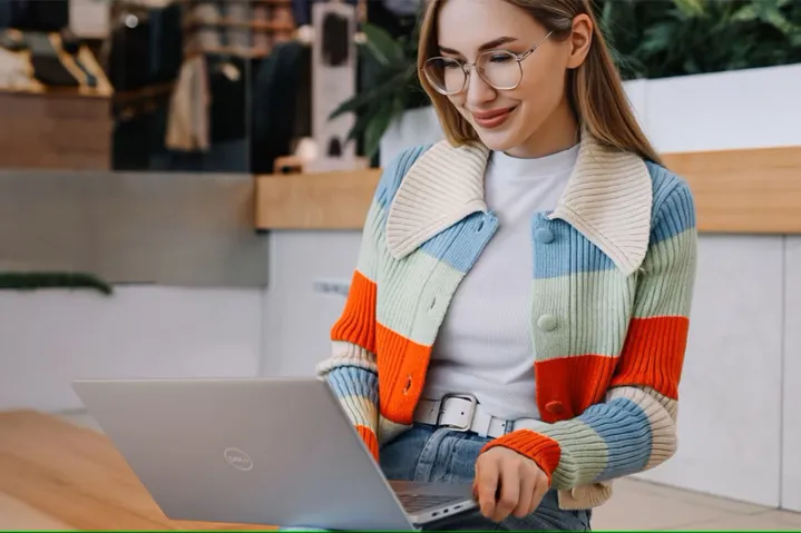 A woman using a Dell Inspiron 14 laptop.