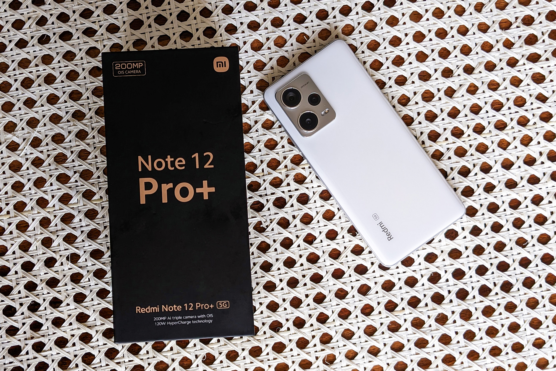 White Xiaomi Redmi Note 12 Pro Plus with its box on a retan table top.