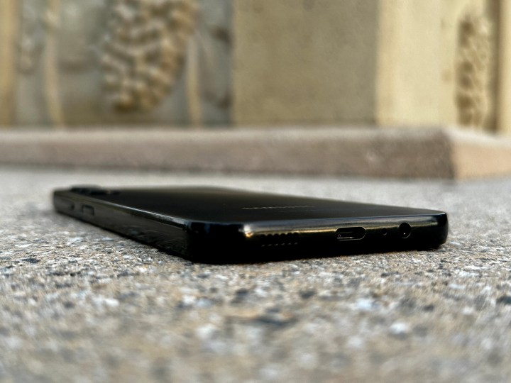 Samsung Galaxy A14 5G कंक्रीट के खंभे पर फ्लैट लेटा हुआ है, जो पोर्ट्स को साइड से थोड़ा कोण पर दिखाता है