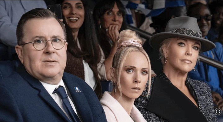 Two women and a man sit at a soccer match in Ted Lasso.