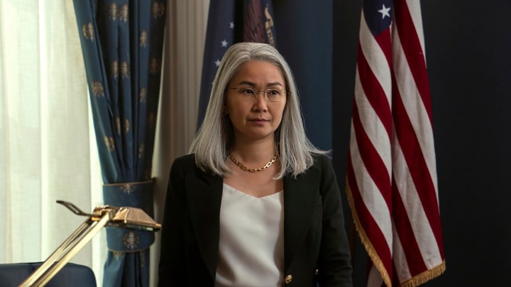 Hong Chau como Diane em The Night Agent, em um escritório da Casa Branca em frente a uma bandeira americana.